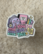 A die-cut sticker featuring a cute school-themed illustration with a purple backpack, books, notebooks, and the words 'You Are Capable' in pastel colors, placed on a beige textured fabric background.