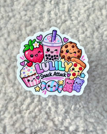 A die-cut sticker featuring cute kawaii illustrations of a strawberry, boba drink, cookie, cupcake, pizza, gummy bear, and candy, with the text 'LULILY Snack Attack' on a textured gray background.