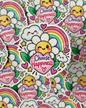 A close-up of a die-cut sticker featuring a smiling sun inside a daisy, surrounded by clouds, stars, hearts, and a rainbow, with the words “Choose Happiness” on a pink heart. Multiple identical stickers are scattered in the background.