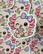 A close-up of a die-cut sticker featuring a cute pink cartoon character with a purple bow and heart details, surrounded by multiple identical stickers in the background.