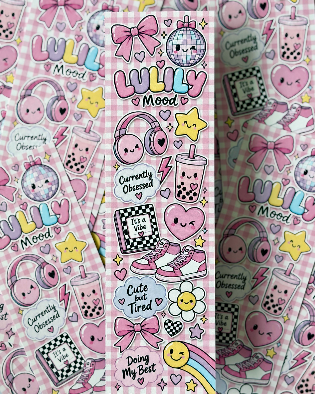 A vertical sticker sheet featuring cute, kawaii-style illustrations on a pink gingham background. The designs include pink bows, a disco ball, headphones, boba cups, sneakers, a flower, a smiley face, and text phrases like 'LULLY Mood', 'Currently Obsessed', and 'Doing My Best'.