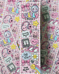 A vertical sticker sheet featuring cute, kawaii-style illustrations on a pink gingham background. The designs include pink bows, a disco ball, headphones, boba cups, sneakers, a flower, a smiley face, and text phrases like 'LULLY Mood', 'Currently Obsessed', and 'Doing My Best'.